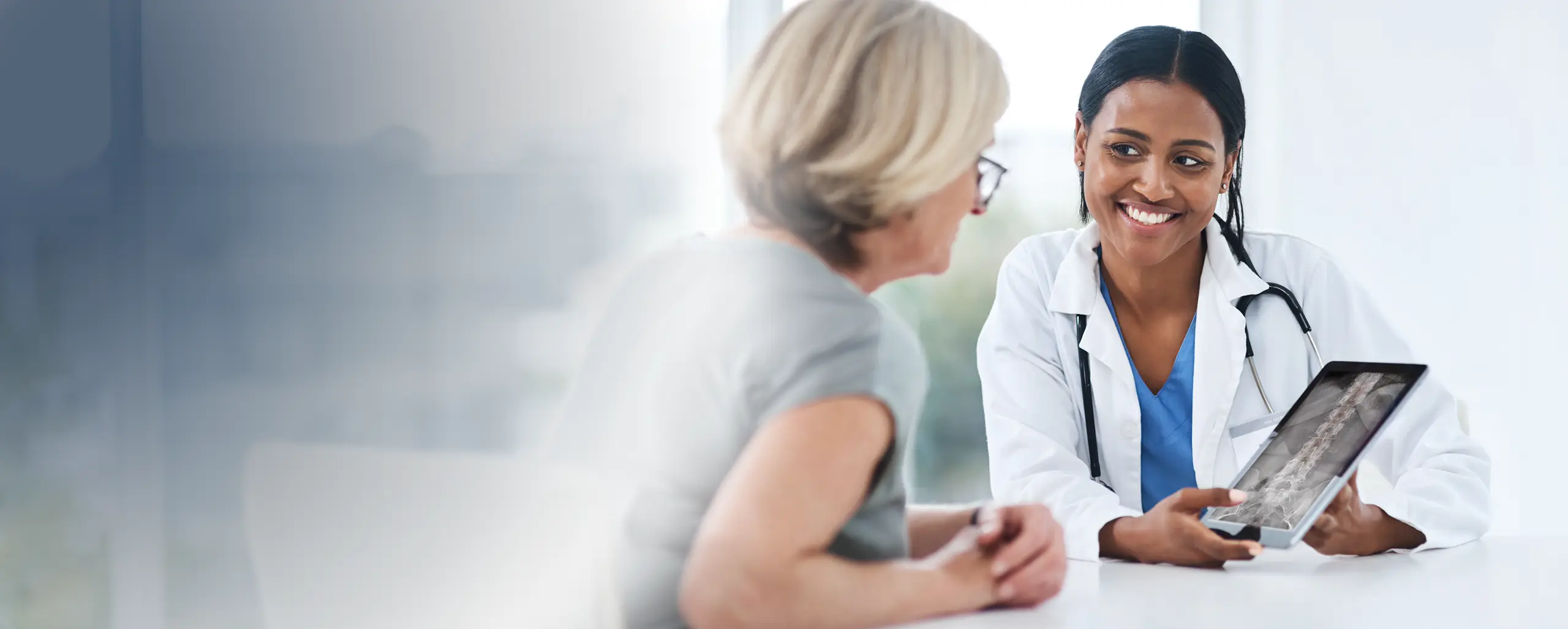 Doctor reviewing digital X-ray images with a patient in a clinical setting